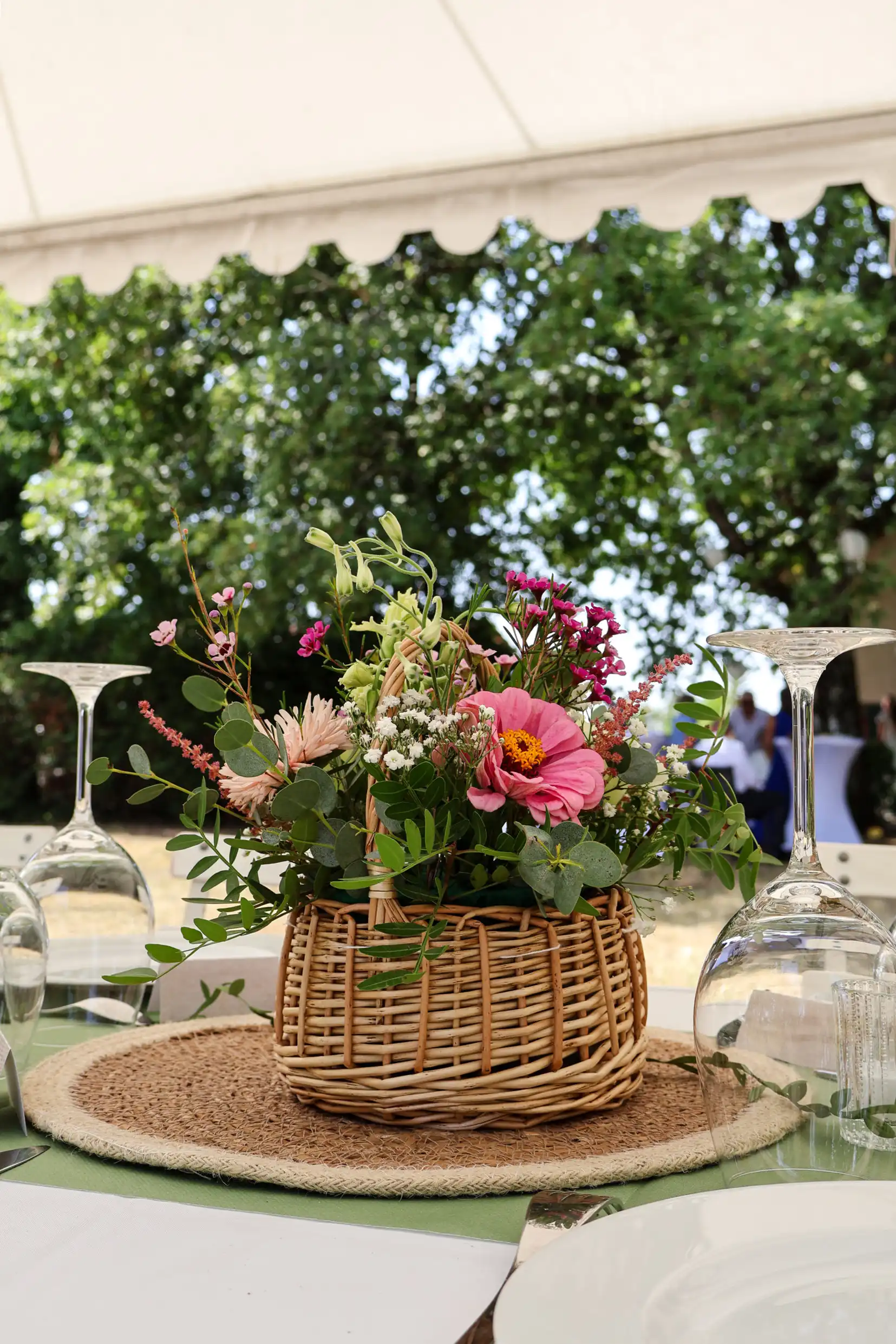 Bouquet de fleurs champêtres dans un panier en osier, verres à pied, décoration de table en extérieur