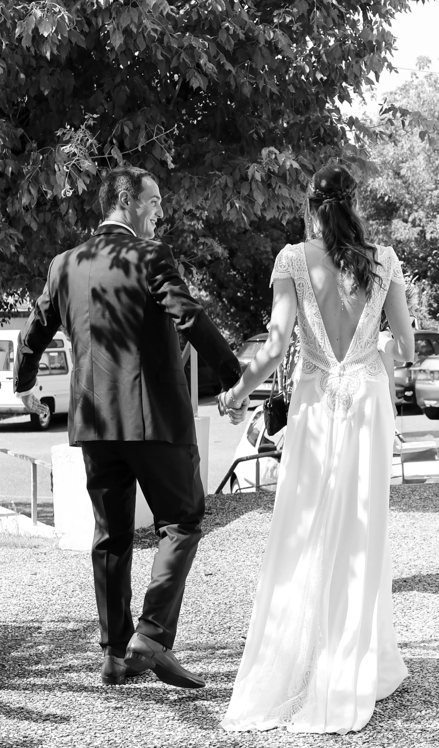 Gros plan noir et blanc sur les mariés et la traîne de la robe de la mariée en mouvement